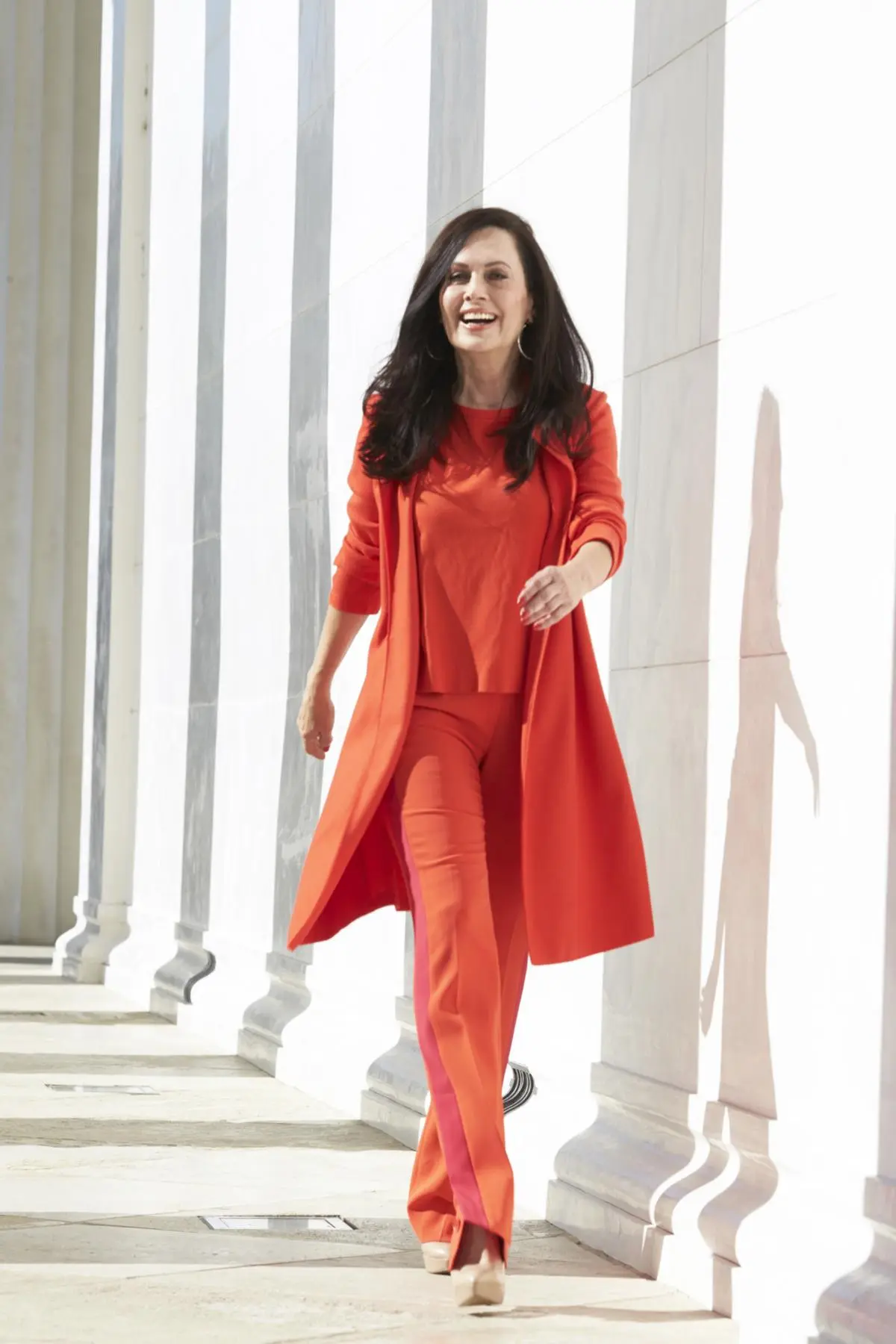 Evelyn Engleder in einem roten Ensemble vor heller Architektur